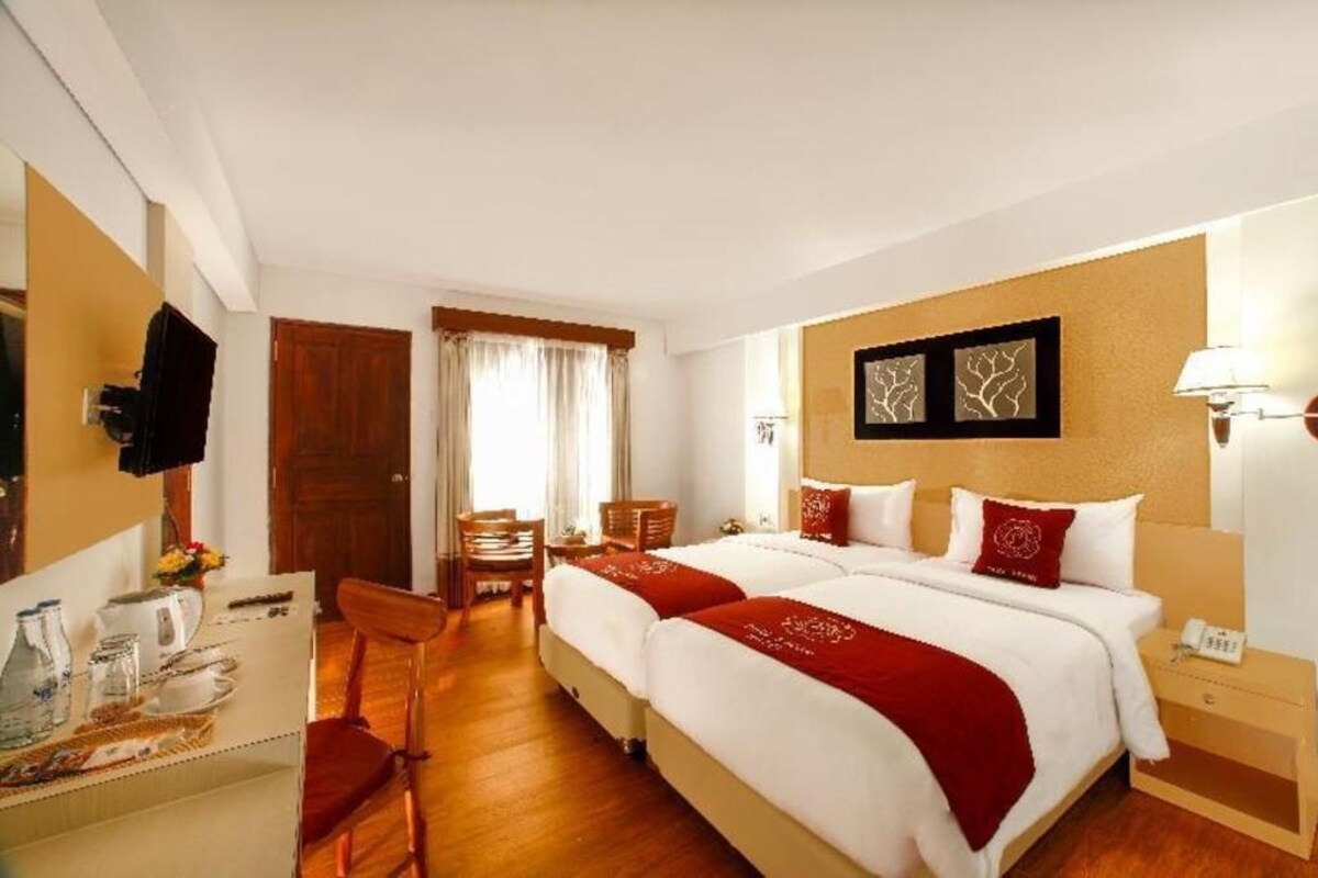 Habitación de hotel con dos camas, un escritorio con silla, un armario y la puerta del baño.