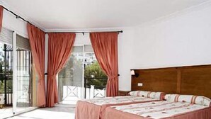 Ein Schlafzimmer mit einem großen Bett, einem Holz-Kopfteil und Blick auf einen Balkon.