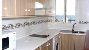 Eine Küche mit Holzausstattung, einer Mikrowelle, einer Waschmaschine und einem Fenster mit Meerblick.