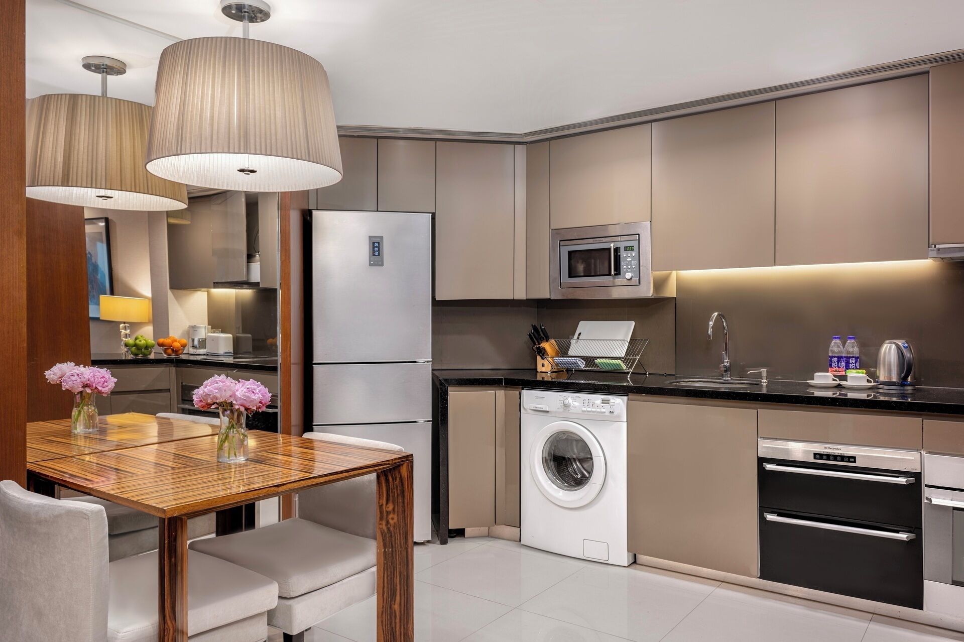 A modern kitchen with a built-in washing machine, a microwave, and a refrigerator.