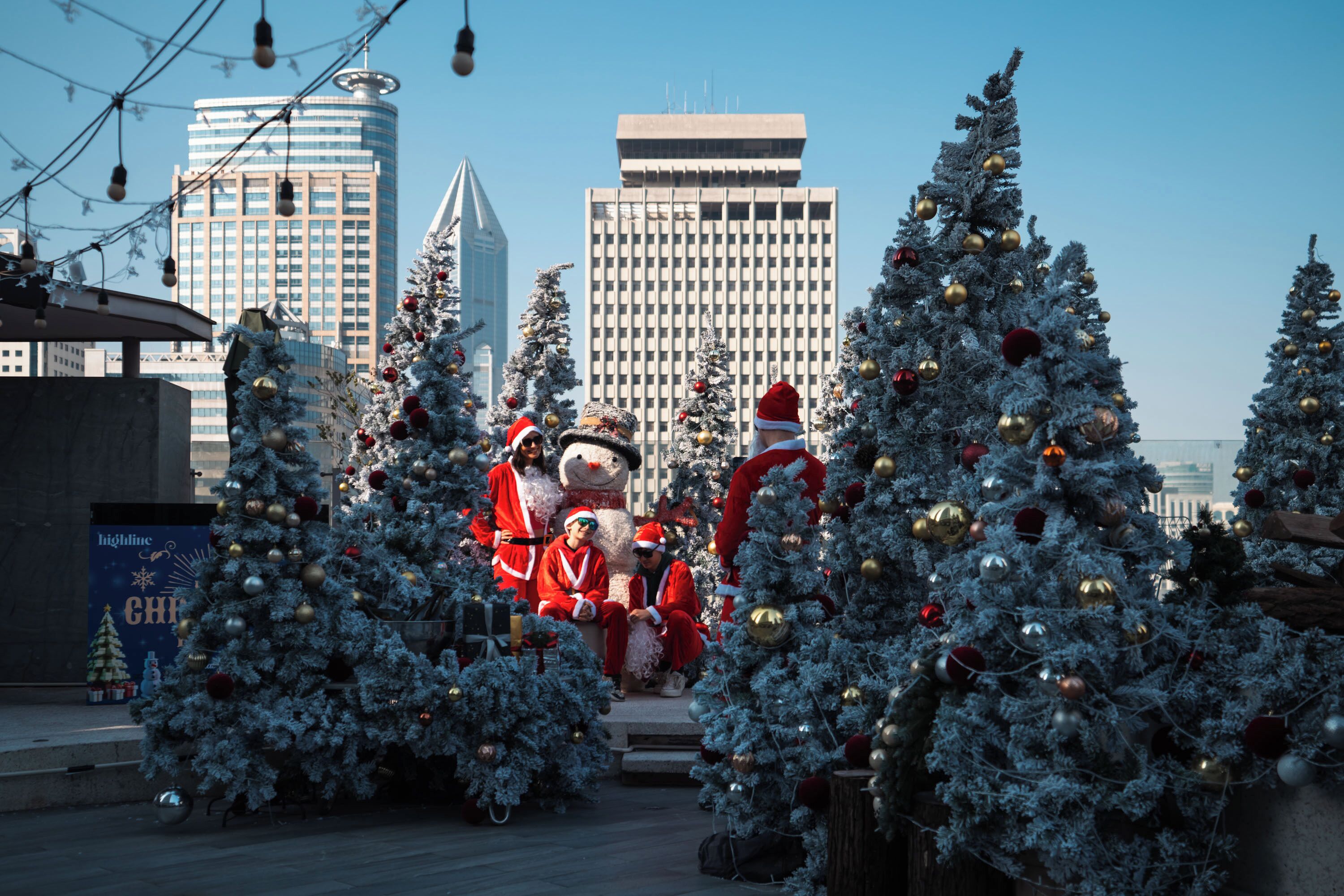 A cityscape with tall buildings, a Christmas tree display, and a Santa Claus figure.