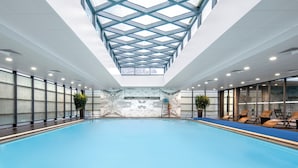 Una piscina interna con soffitto a lucernari, pareti in marmo e poltrone a bordo.
