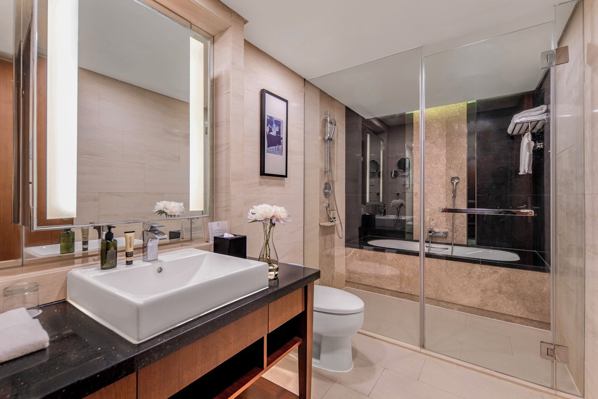 A modern bathroom with a large mirror, a white sink, a glass shower enclosure, and a toilet.