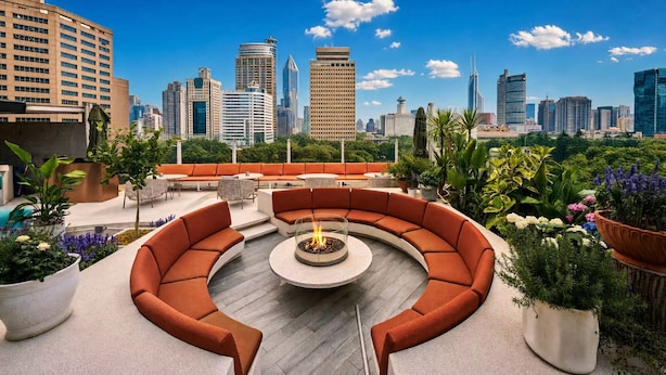 Una terrazza panoramica con un'area salotto circolare, un braciere e vista sullo skyline della città.