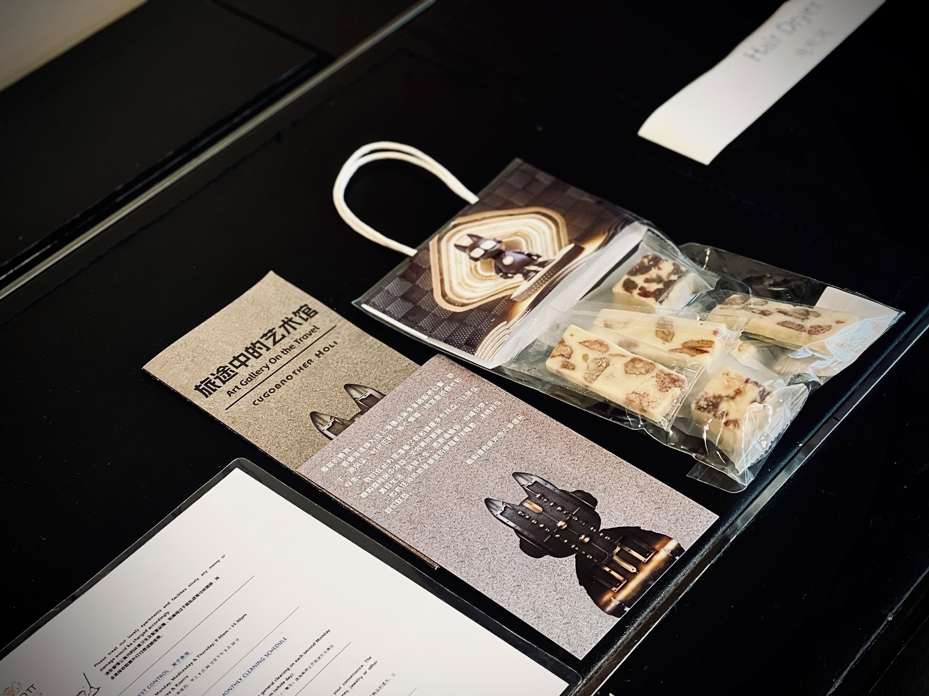 A table with a business card, a menu, and a small bag of chocolates.