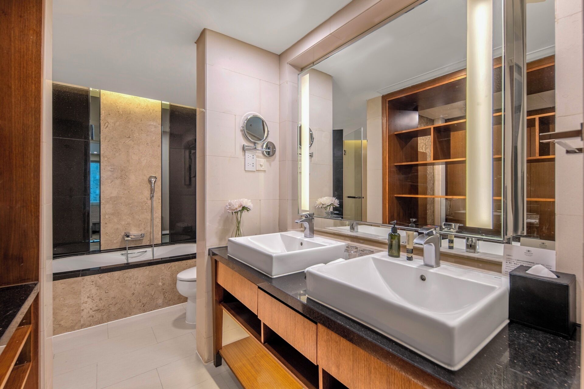 A modern bathroom with two sinks, a shower, and a large mirror.
