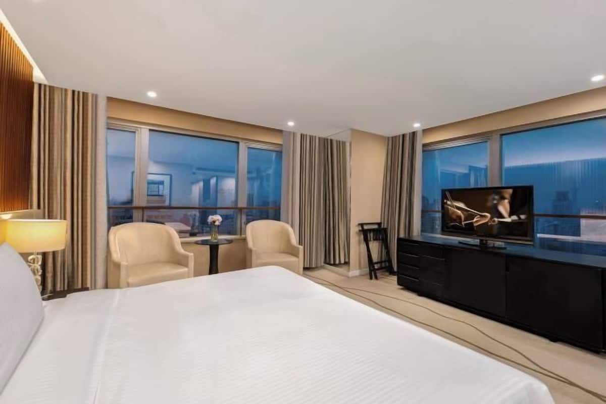 Ein Hotelzimmer mit einem großen Bett, einem Fernseher, einem Schreibtisch und zwei Stühlen.