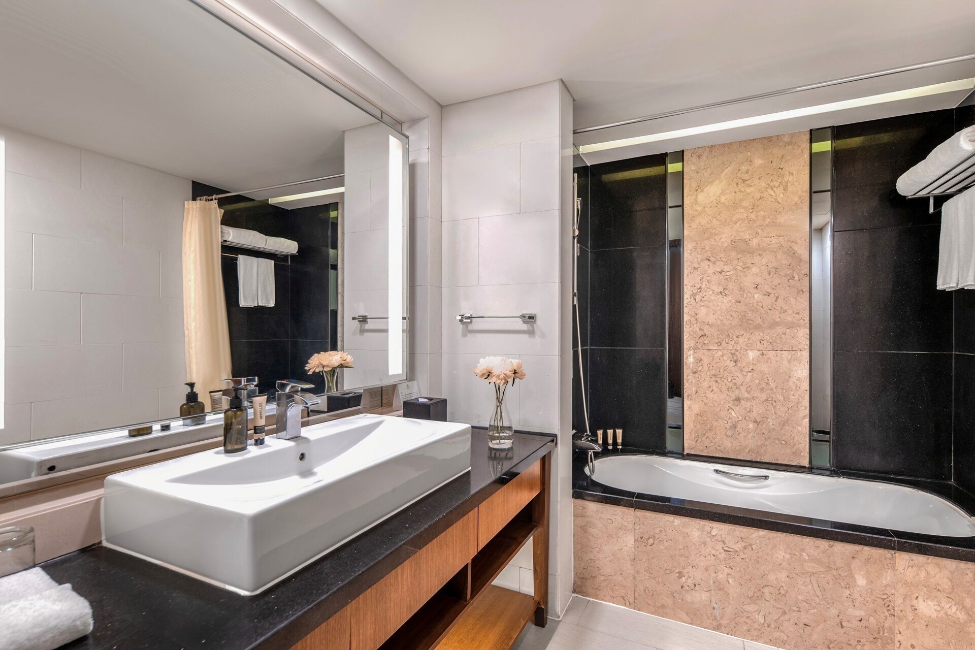 Ein modernes Badezimmer mit zwei Waschbecken, einem großen Spiegel, einer Badewanne und einer Duschkabine.