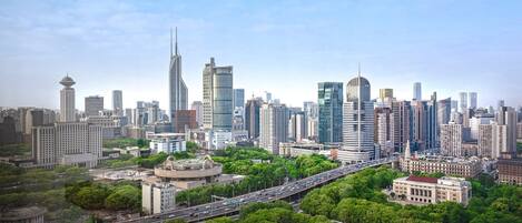 A cityscape with modern high-rise buildings, a highway, and surrounding greenery.