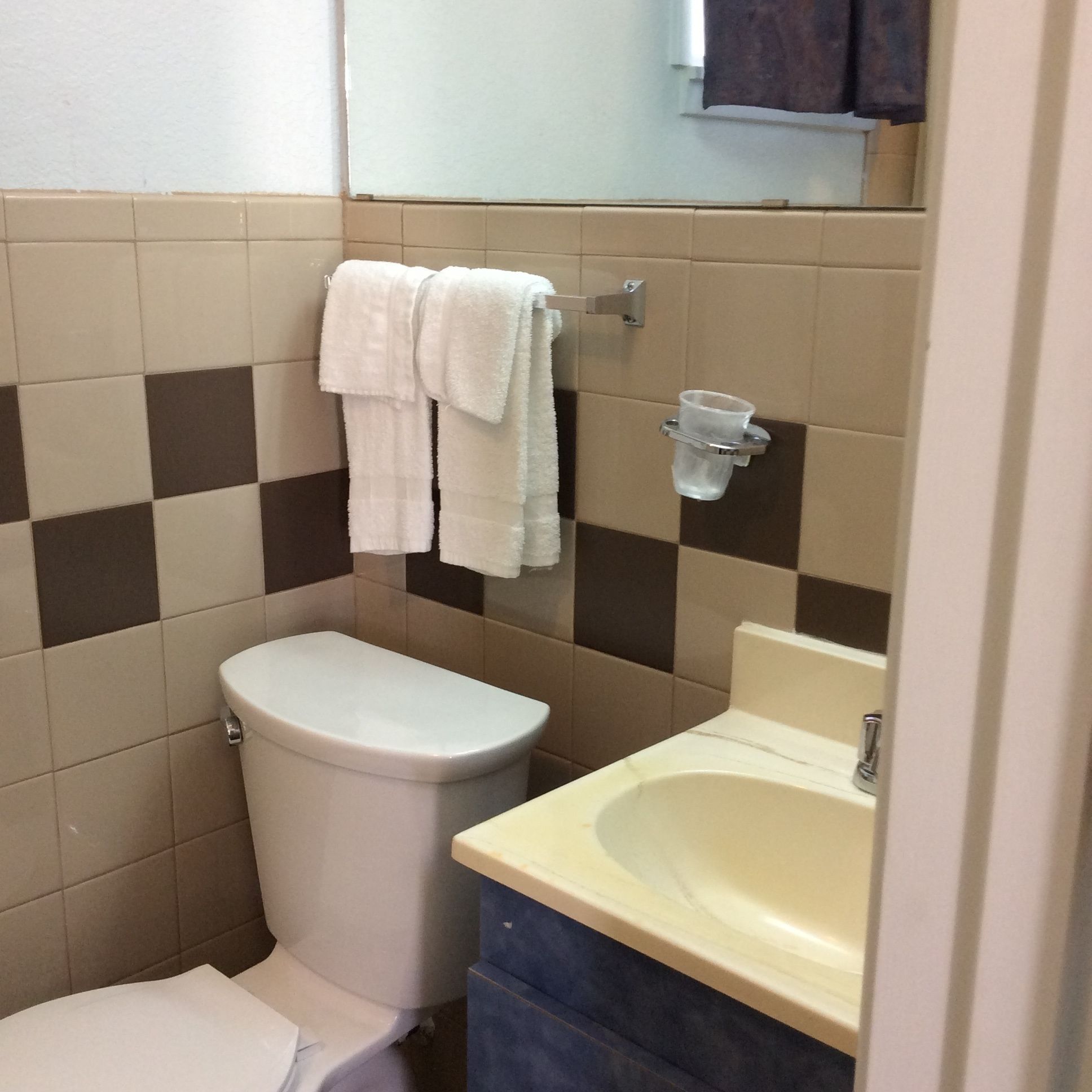 Un baño pequeño con inodoro, lavamanos y barra para toallas.