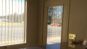 Una habitación con ventana y puerta, una encimera con un portátil, y el reflejo de un coche rojo en el exterior.