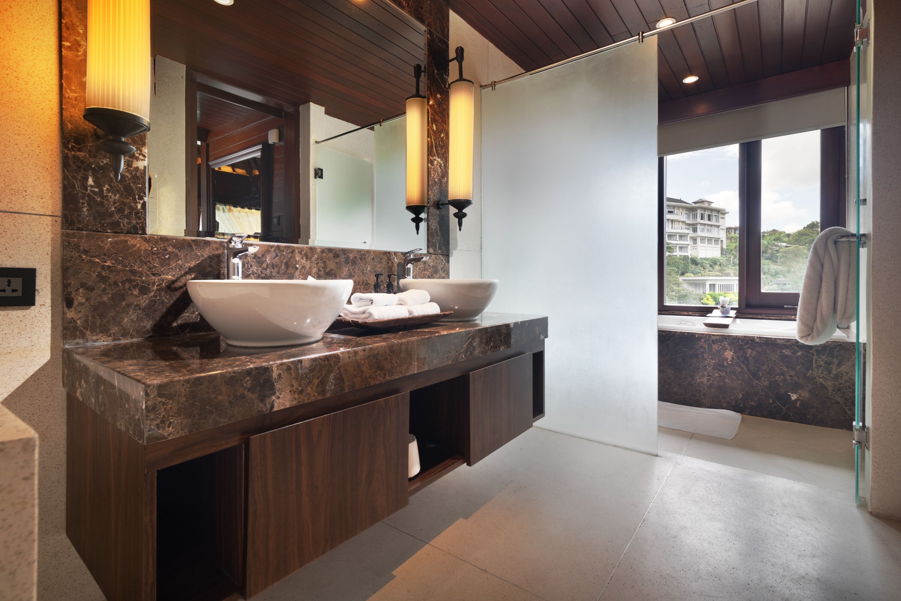 Un bagno moderno con un elegante mobile lavabo in marmo, due lavandini e uno specchio grande.