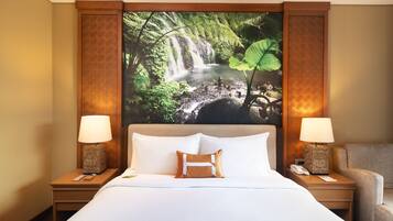 A hotel room with a large bed, two bedside tables with lamps, a chair, and a wall with a nature-themed mural.