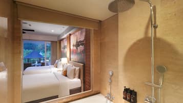 A hotel room with a large mirror, a bathtub, a shower, and a view of a garden.