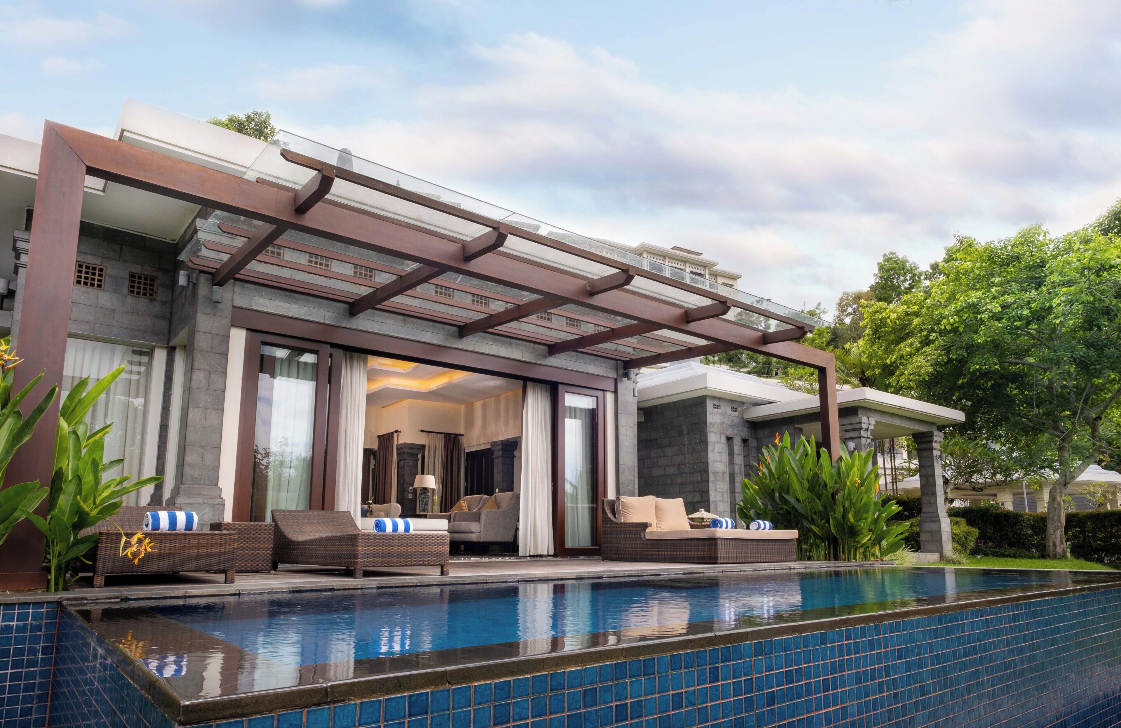 A modern house with a swimming pool, outdoor seating, and a covered patio.