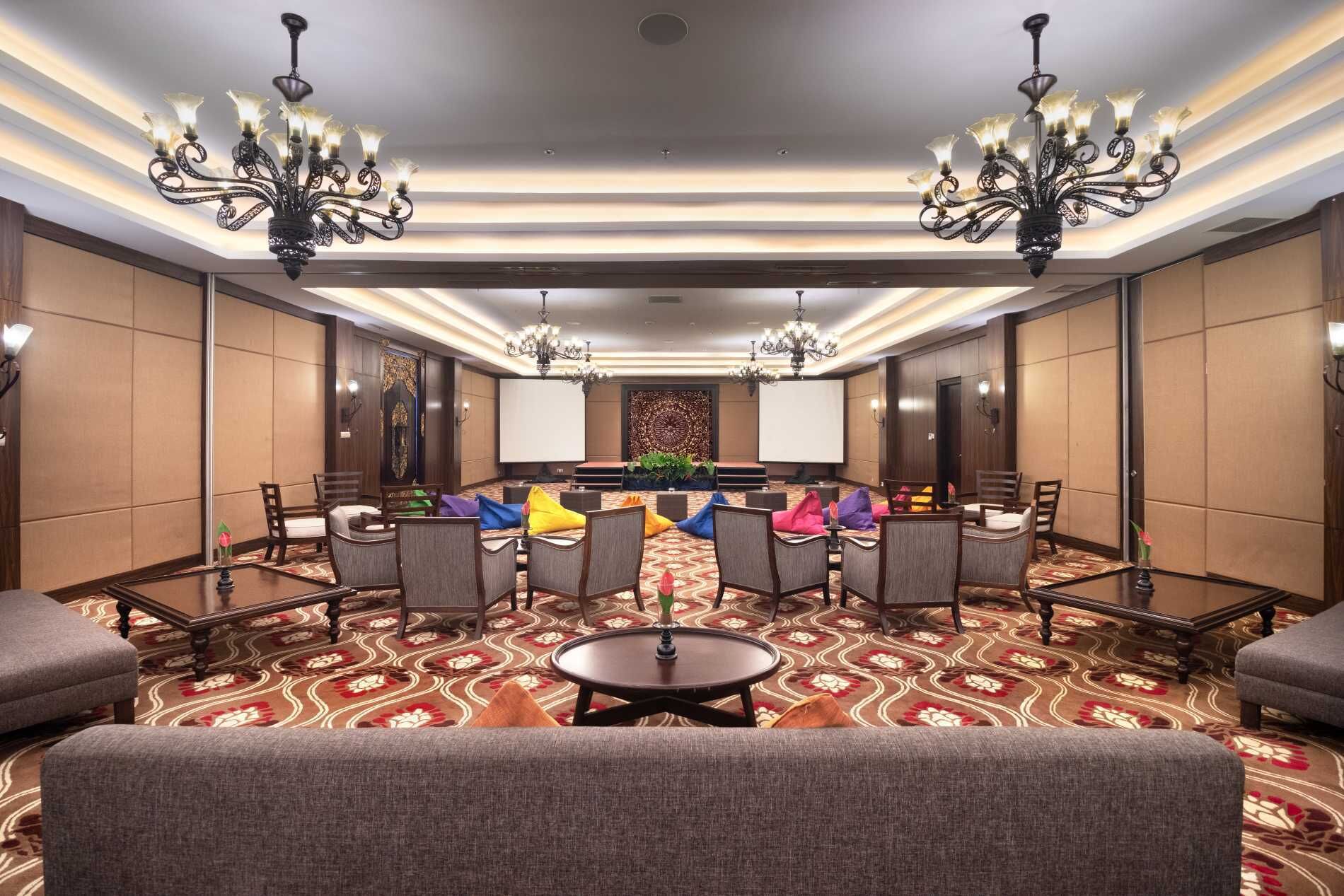 A conference room with a large table, multiple chairs, and two chandeliers.