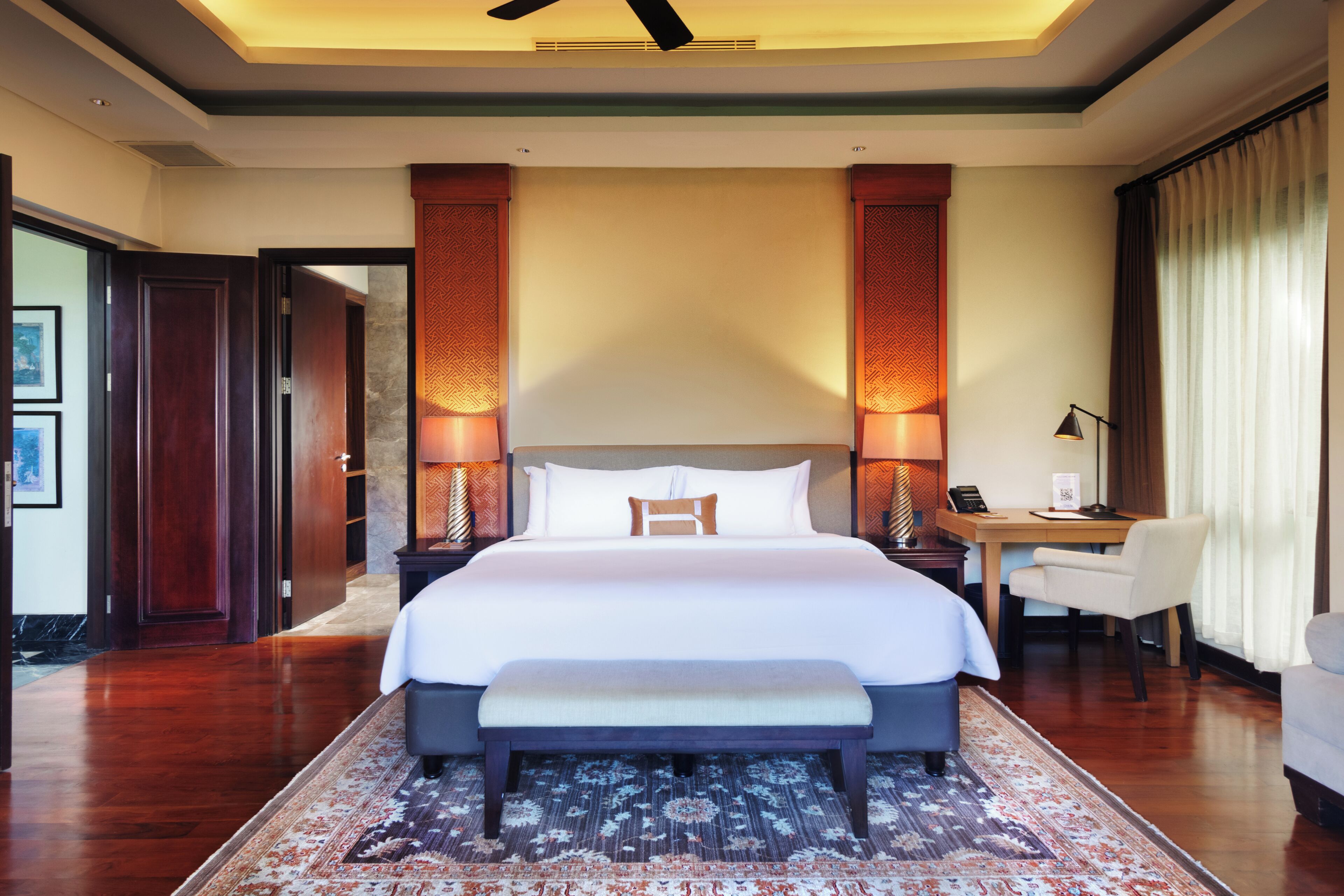Une chambre d’hôtel avec un grand lit, des lampes de chevet, un bureau et une chaise.