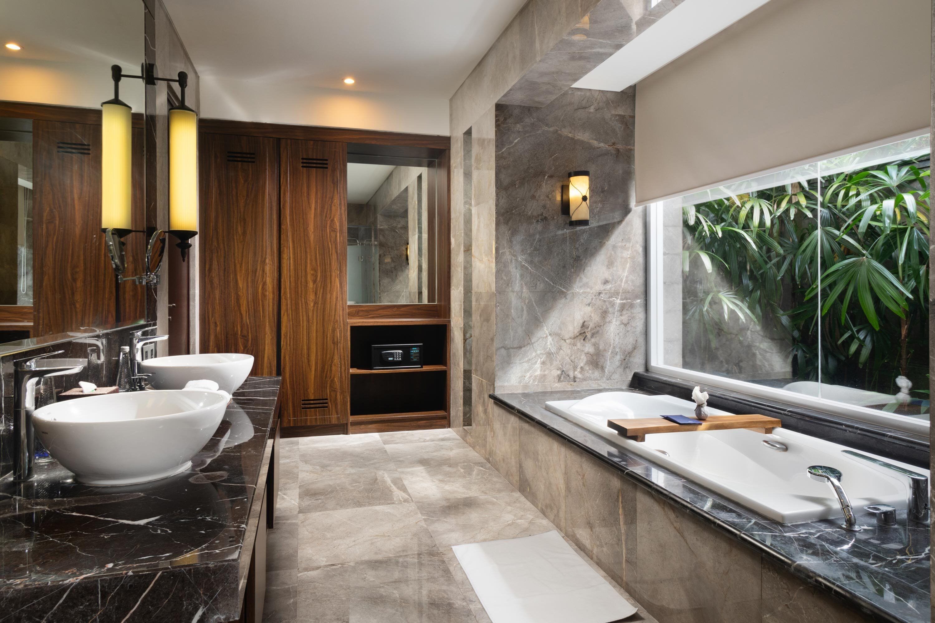 Un baño moderno con un espejo grande, dos lavamanos, un tocador y una zona de ducha.
