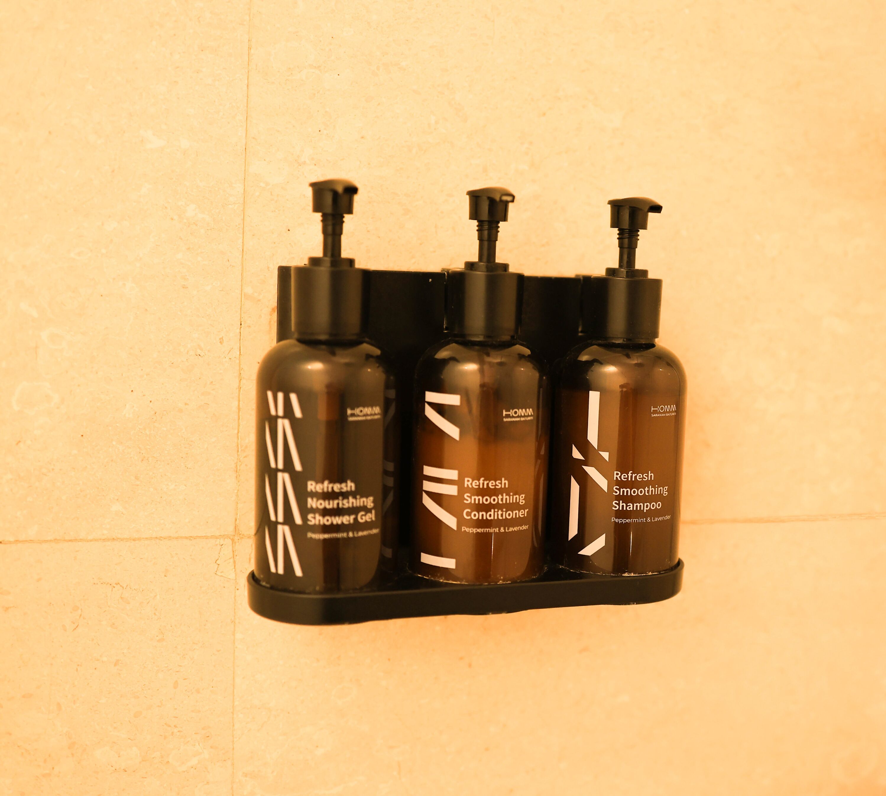 A wall-mounted shelf with three black bottles of men's grooming products.