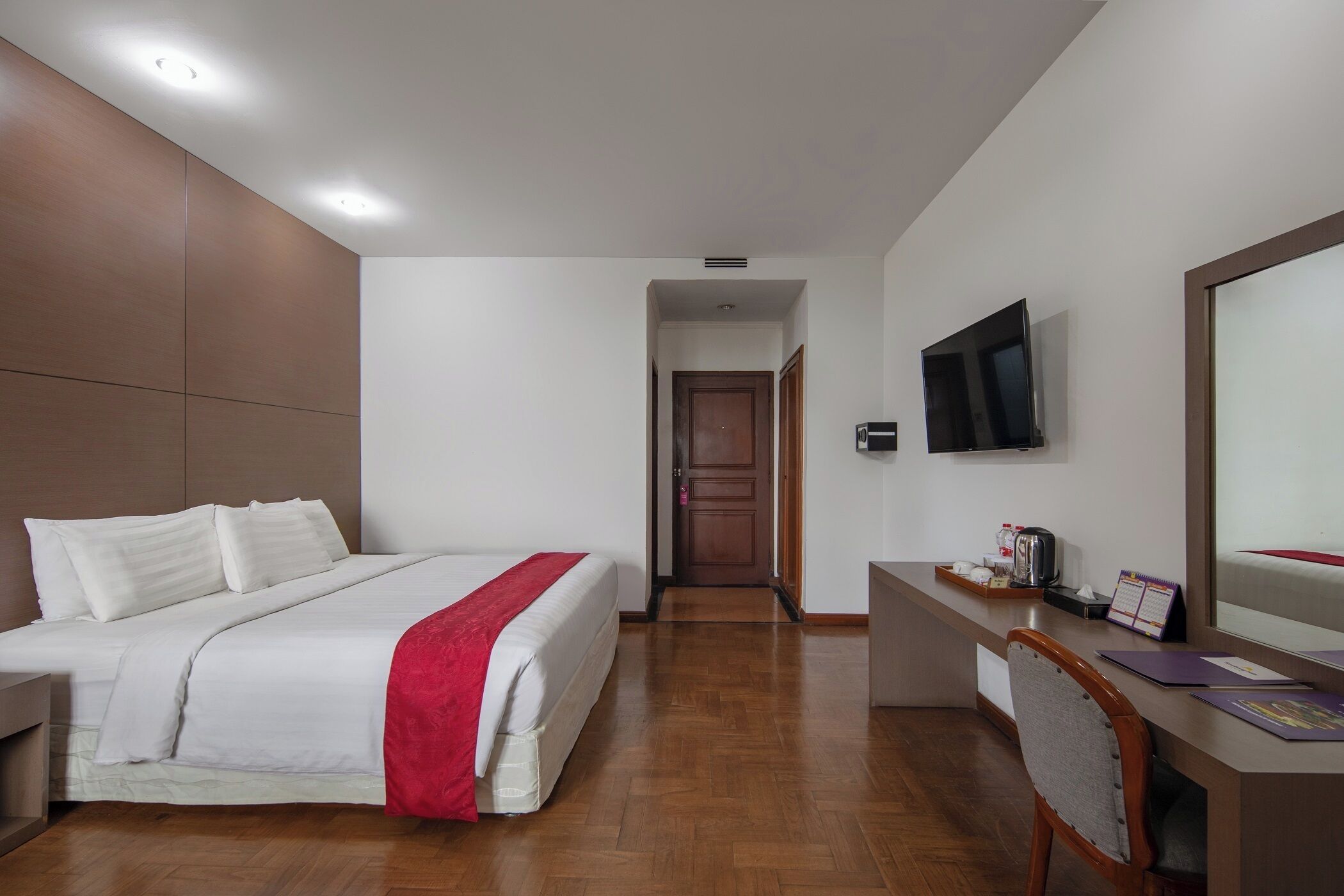 Quarto de hotel com cama, escrivaninha e televisão.