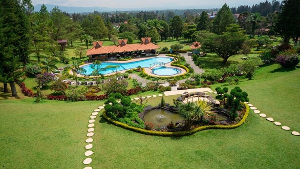 Un resort con una piscina grande, jardines ajardinados y un pabellón.