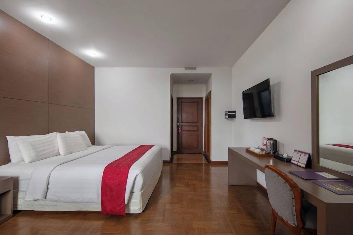 Una habitación de hotel con una cama, un escritorio, una silla, un televisor y una puerta que da a otra habitación.