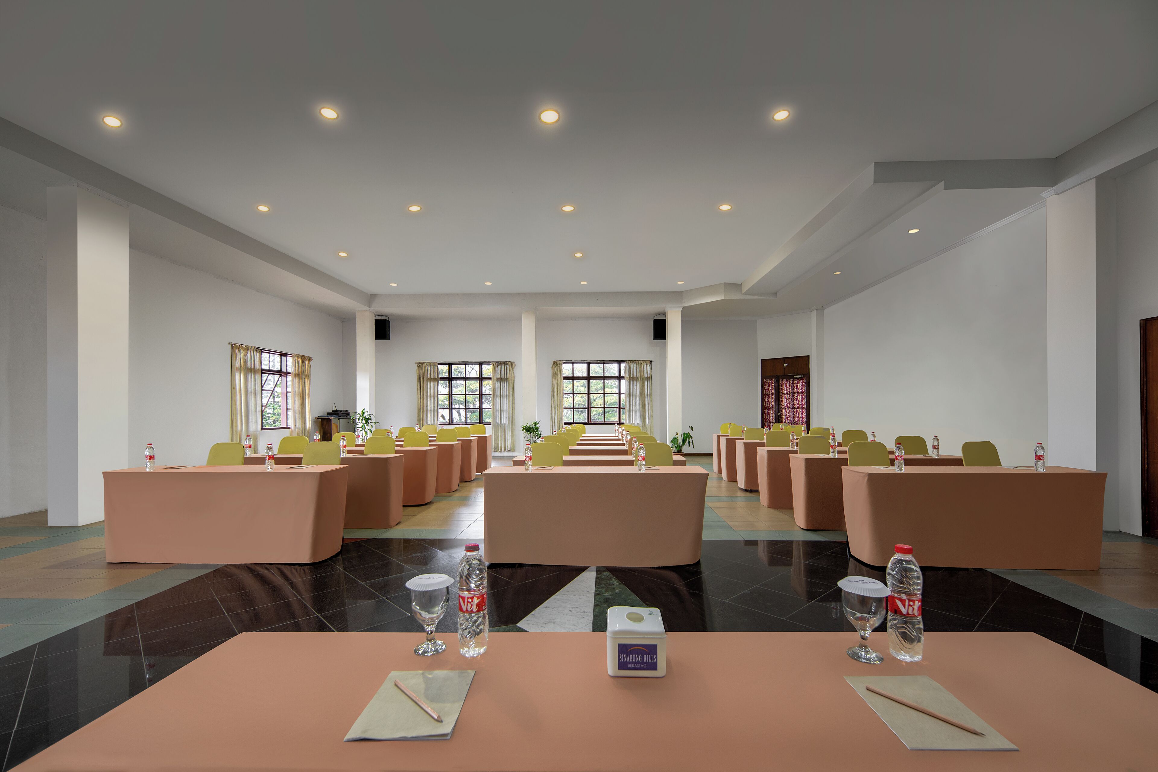 Un salón de conferencias con varias mesas, sillas y un escenario.