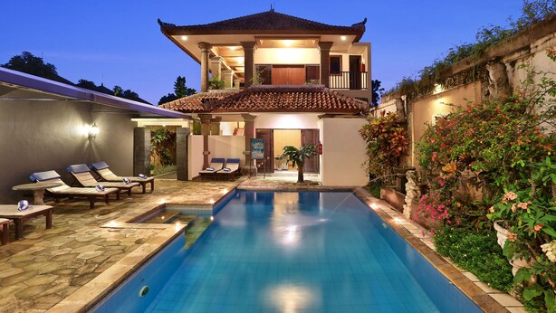 A two-story house with a swimming pool, lounge chairs, and a garden. - The Batu Belig Hotel & Spa (Keroboken Kelod)