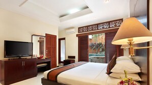A hotel room with a large bed, a TV, a wooden cabinet, and a decorative lamp. - The Batu Belig Hotel & Spa (Keroboken Kelod)