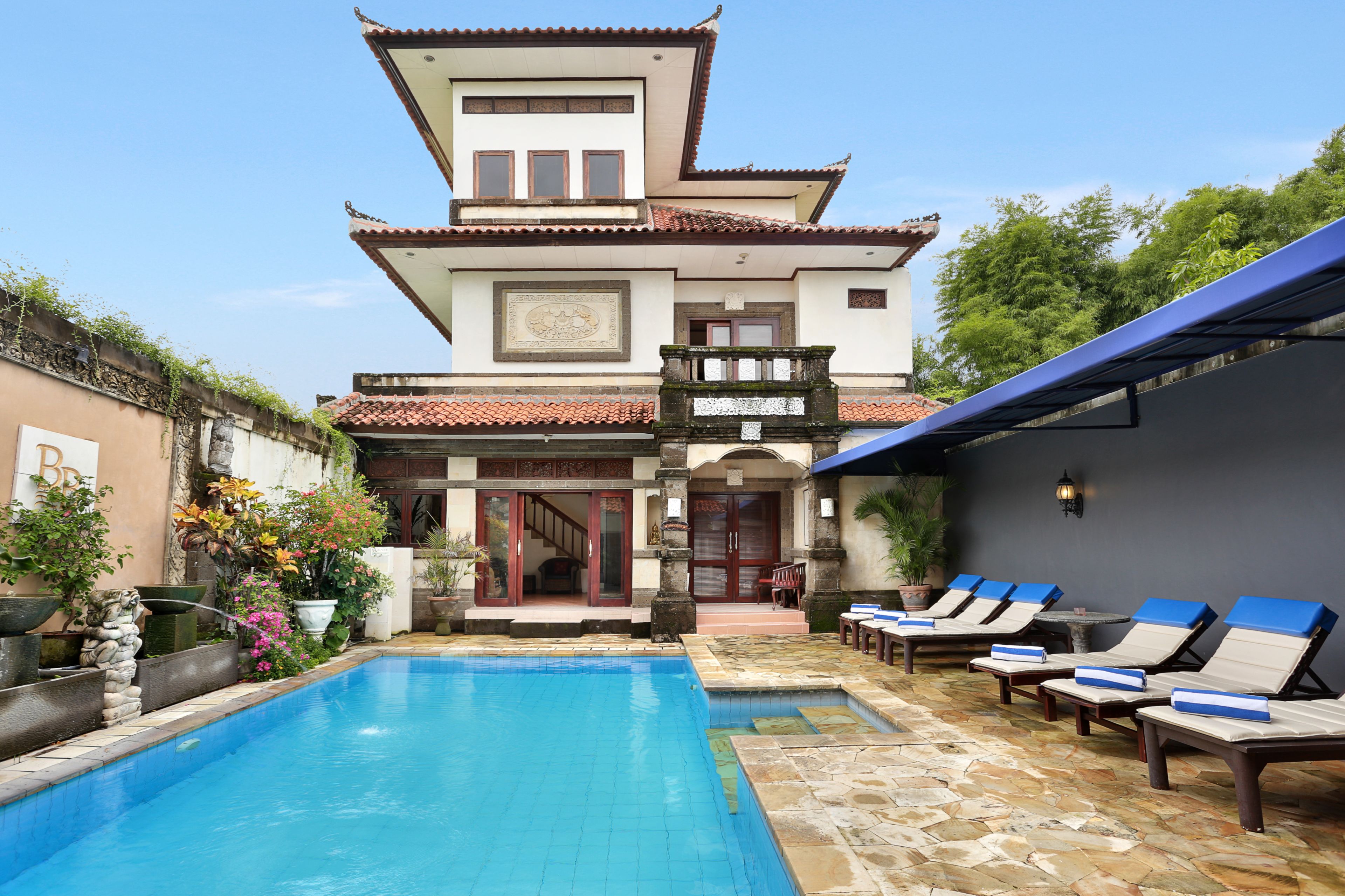 A traditional building with a swimming pool and lounge chairs.