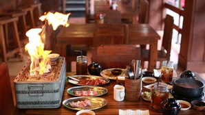 A dining table with a grill, various dishes, and condiments. - The Batu Belig Hotel & Spa (Keroboken Kelod)