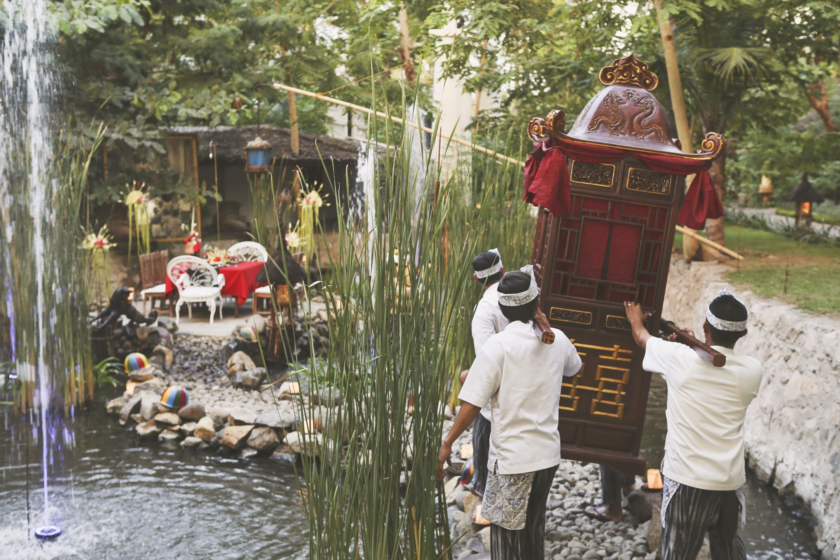 A traditional ceremony with a decorated carriage, a pond, and a rustic setting.