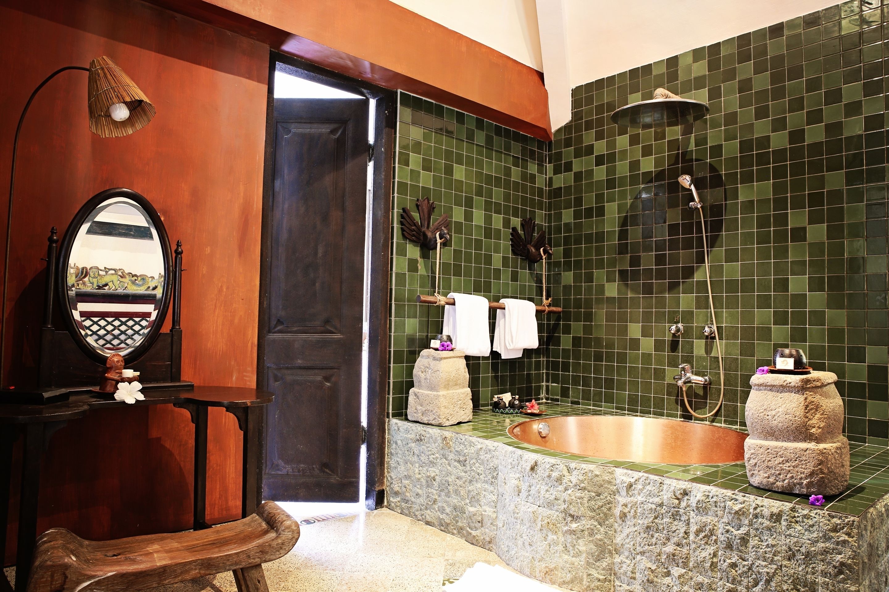 Un baño con una bañera grande, un tocador de madera, un espejo y una zona de ducha con azulejos verdes.
