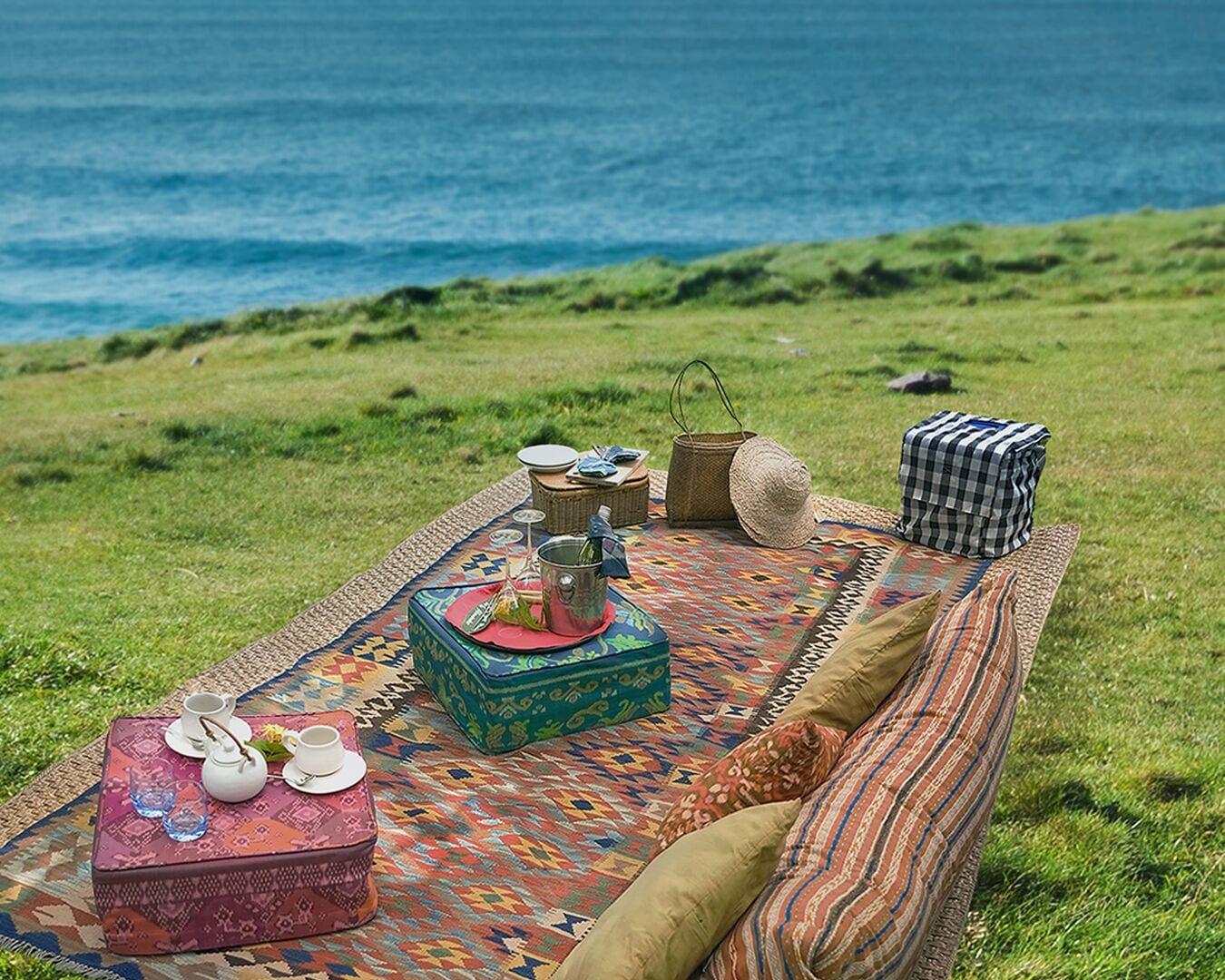 A picnic setup on a grassy area with a view of the ocean.