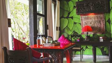 A room with a red table, chairs, and a green leafy wall.