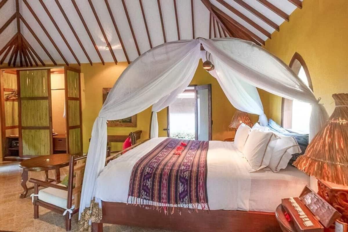 Een slaapkamer met hemelbed, houten meubels en uitzicht naar buiten.