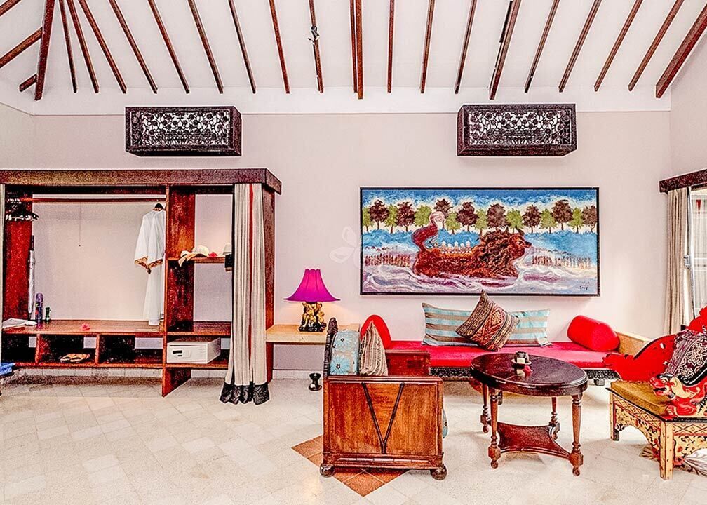 A room with a bed, a sofa, a table, and a painting on the wall.