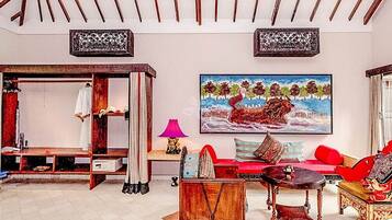 A room with a bed, a sofa, a table, and a painting on the wall.