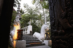 Una escalera con una estatua de un caballo blanco, rodeada de tallados ornamentales y un exuberante fondo verde.