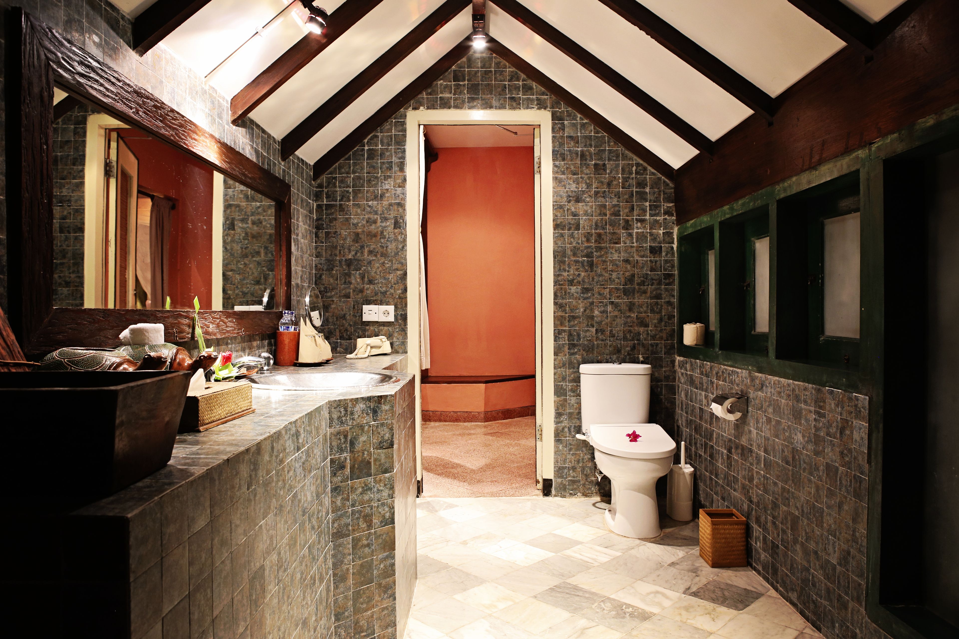 A bathroom with a large sink, a toilet, and a mirror.