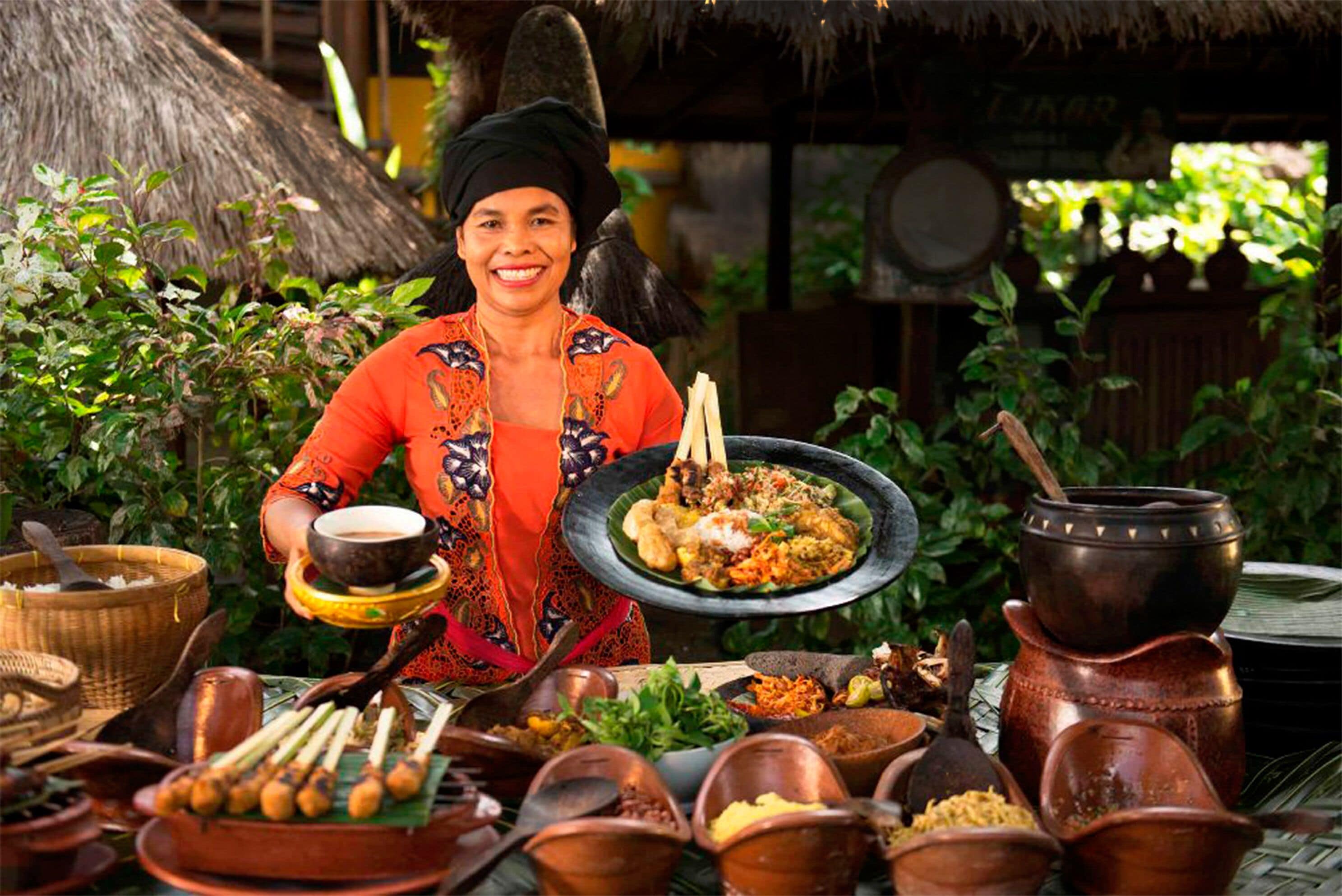 A person serving food on a table with various dishes and utensils.