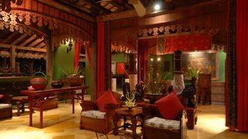 A traditional interior with wooden furniture, a central table, and decorative plants.