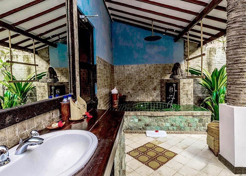 A bathroom with a large mirror, a sink, a bathtub, and a shower area.