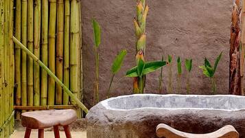 A stone bench, a bamboo fence, and a concrete planter with green plants.