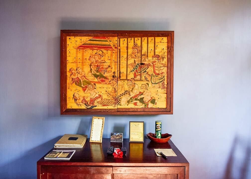 A traditional Chinese painting hanging on a wall above a wooden desk with various items on it.