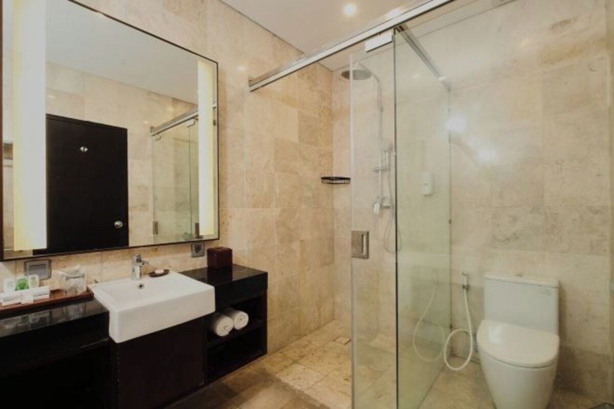 A modern bathroom with a glass-enclosed shower, a white sink, and a large mirror.