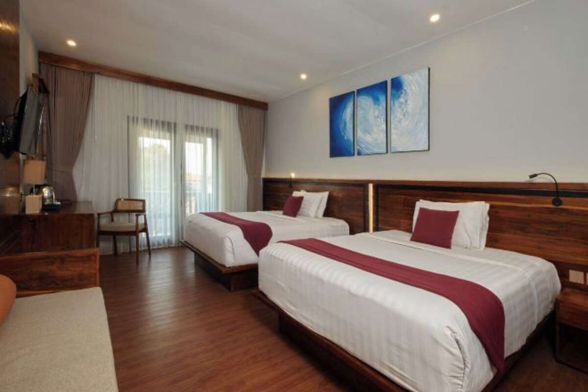 A hotel room with two beds, a wooden headboard, a desk, and a chair.