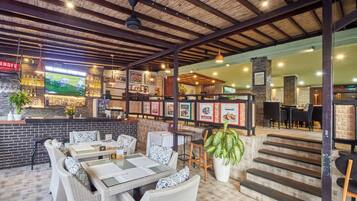 Ein Restaurant mit Korbmöbeln, einer Bar und einer Treppe zu einer oberen Ebene.
