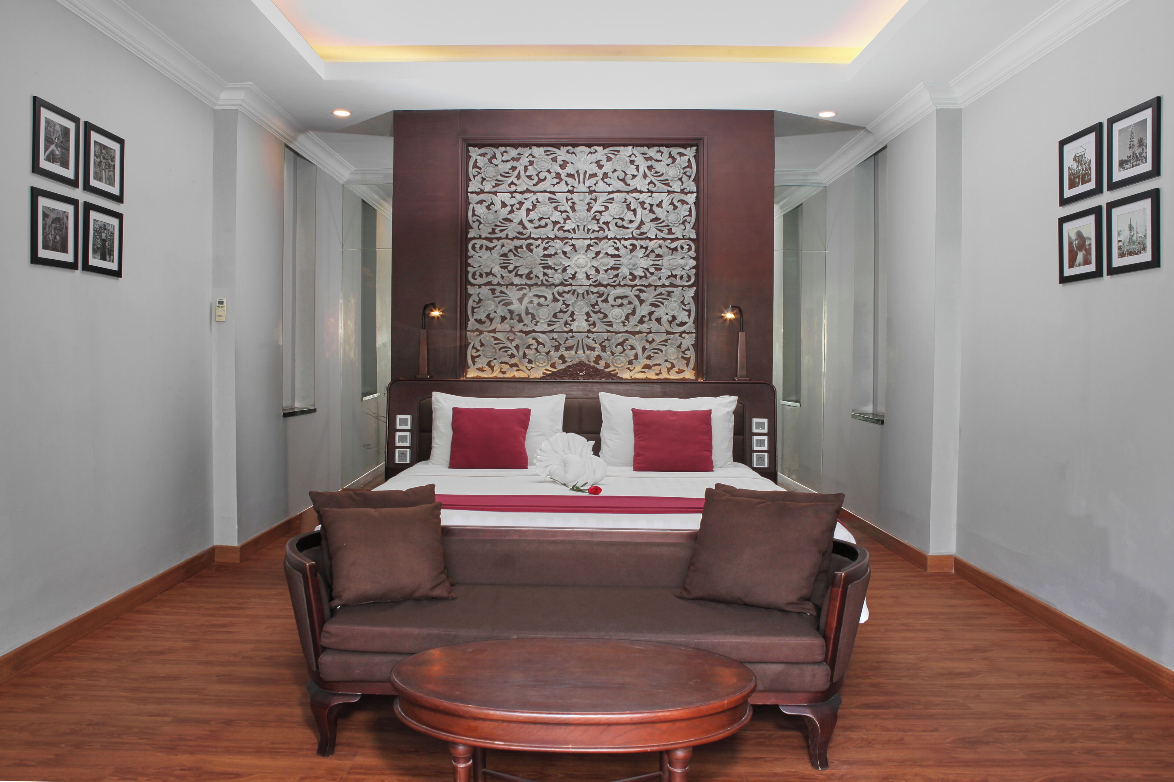 A hotel room with a large bed, a brown sofa, a round coffee table, and a decorative wall panel.