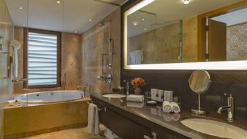 A modern bathroom with a large bathtub, two sinks, a vanity, and a large mirror.